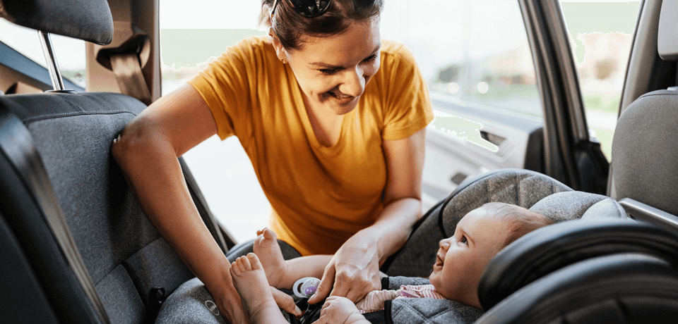 Mother Strapping Baby Into Car Seat